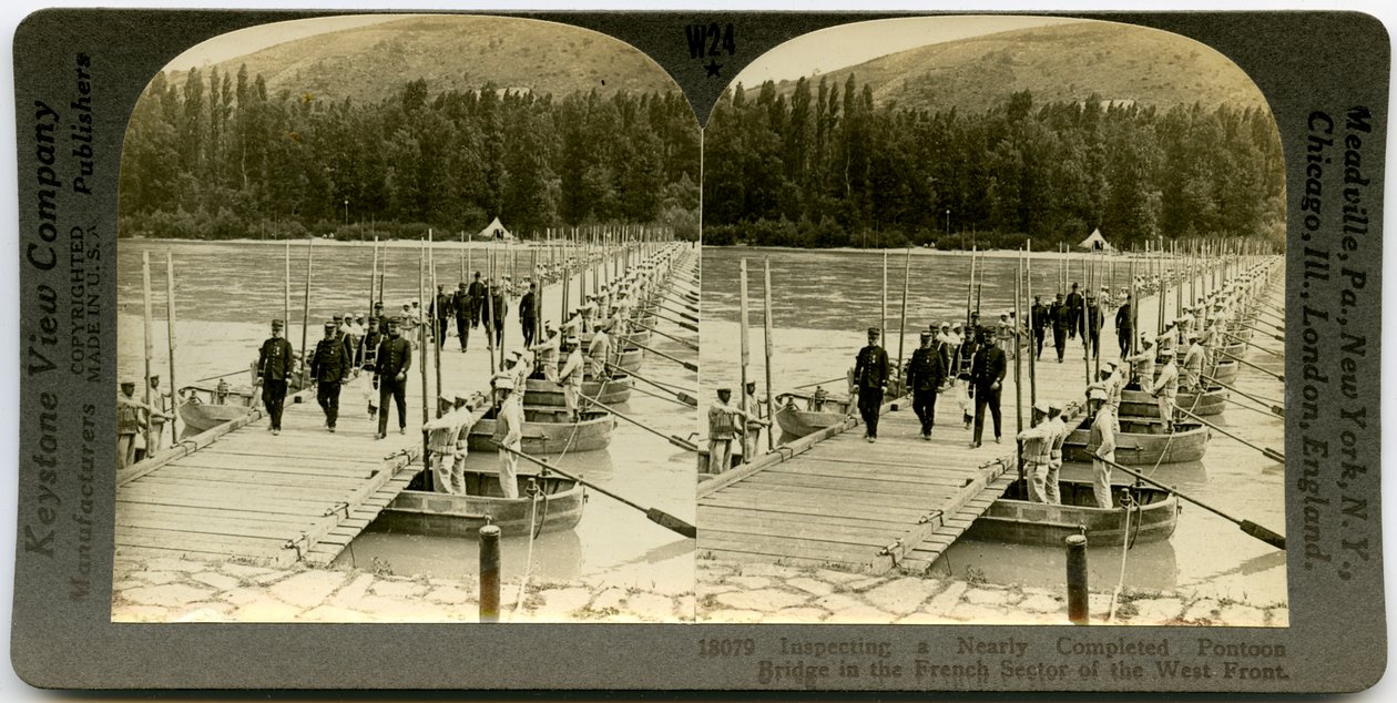 Carte stéréoscopique horizontale sépia montrant des officiers en uniforme traversant un ponton avec des hommes se tenant dans les pontons de chaque côté du pont. Stéréographe Keystone numéro 18079 - Keystone View Company