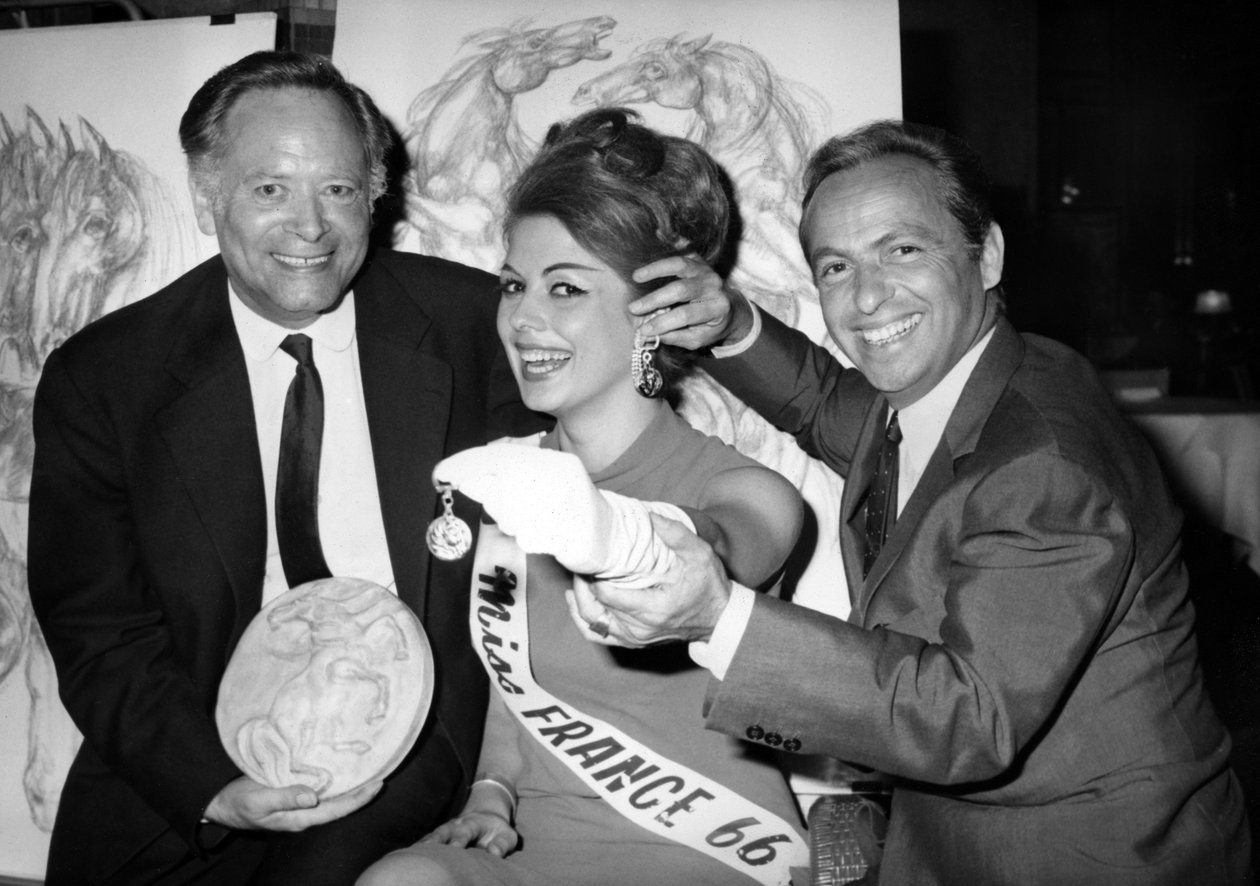 René Bollinger (à gauche) et Guy Lux entourent Monique Boucher « Miss France » à qui ils viennent de remettre un porte-clés « Talisman du turfiste » lors de l
