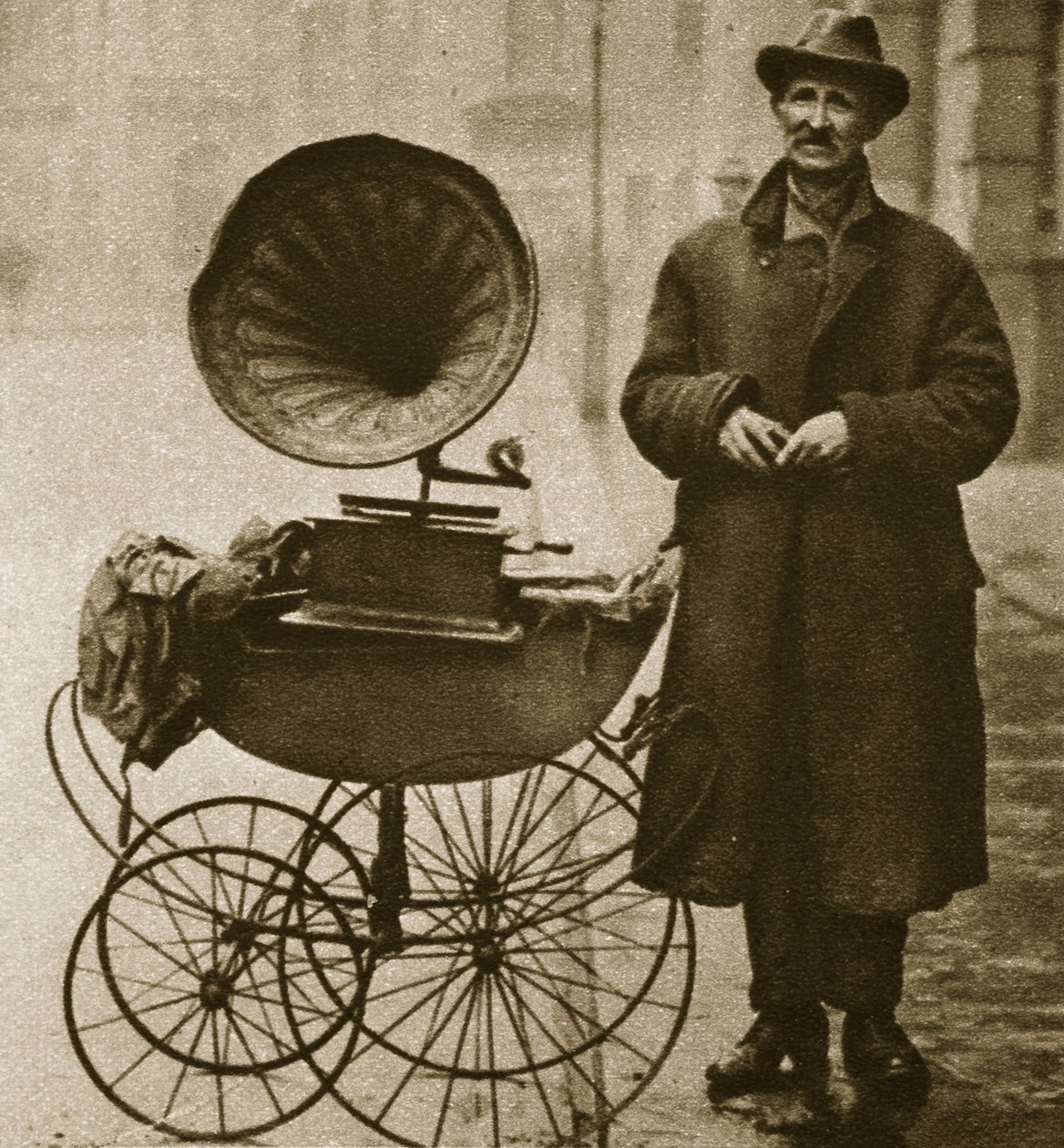 Un colporteur de rue divertit avec un gramophone, transporté dans une poussette - English Photographer