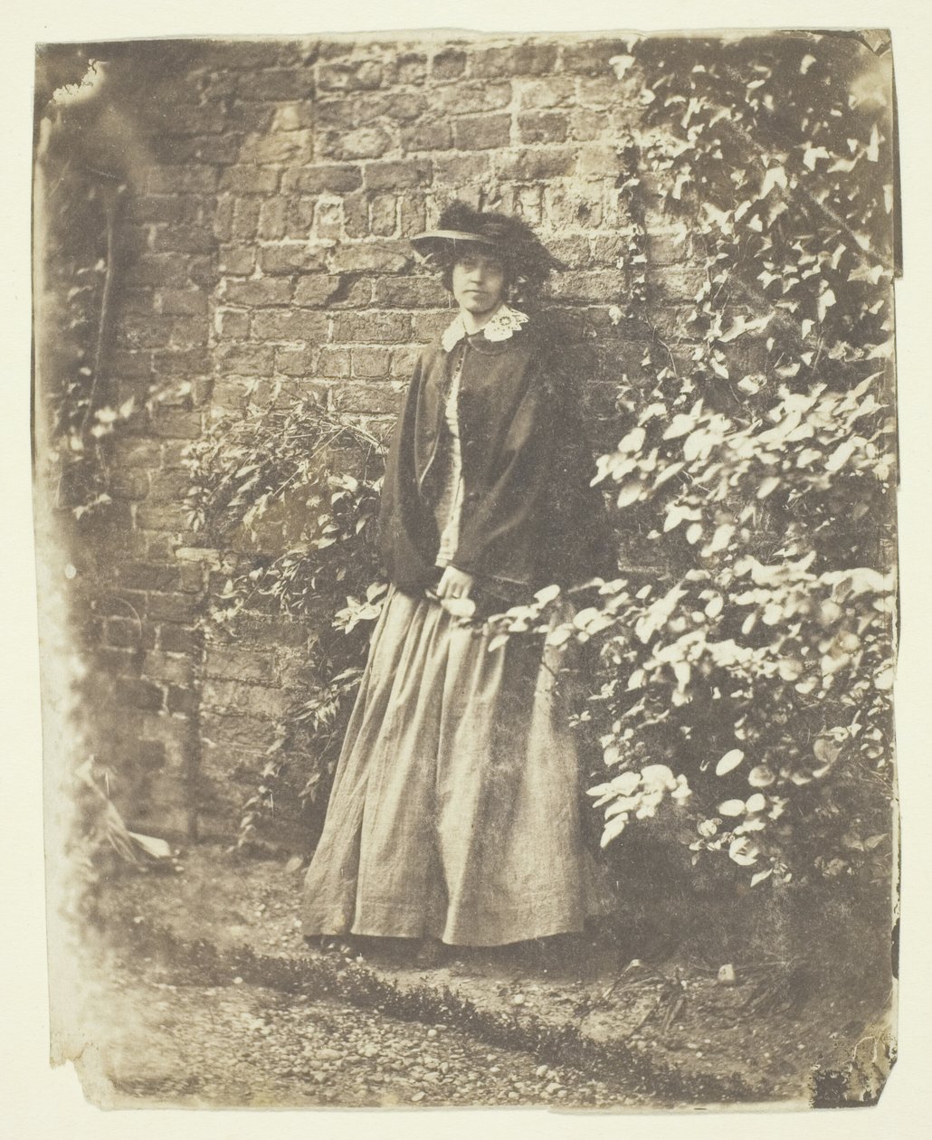Mme Craik appuyée contre un mur et des buissons - Unknown