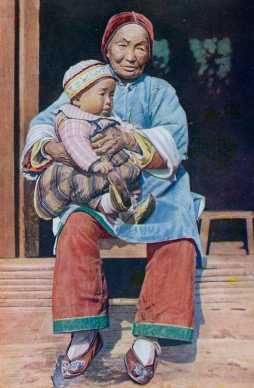 Grand-mère chinoise, portant un pantalon, avec son petit-fils - English Photographer